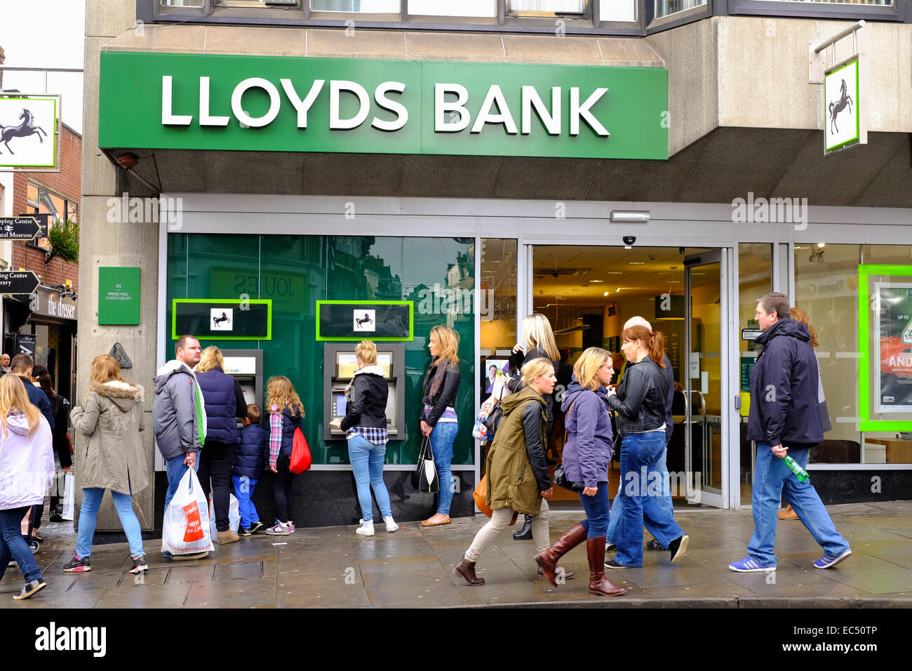 Le persone che usano le macchine di contanti e oltrepassando la Lloyds Bank, Shrewsbury, Shropshire, Inghilterra. Foto Stock