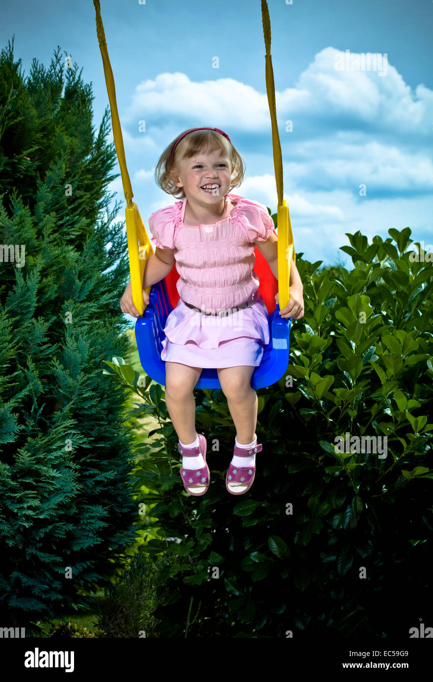 Un 3,5 anni ragazza oscillanti in giardino Foto Stock