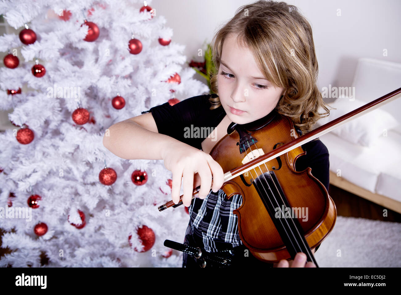 Una giovane ragazza suona il violino a albero di Natale Foto Stock