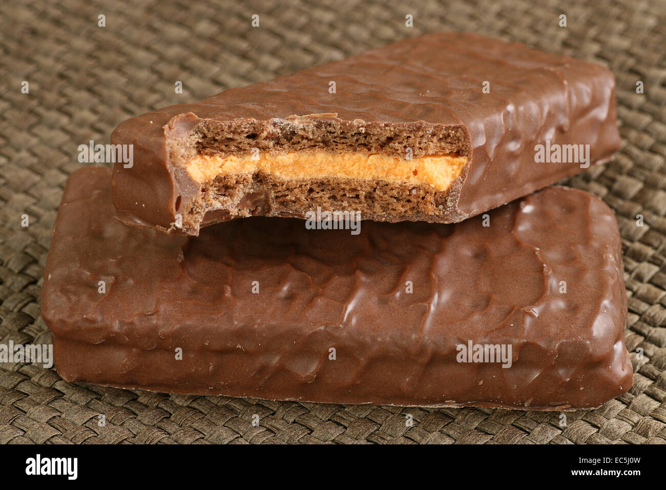 Due ricoperti di cioccolato biscotti riempito con crema di colore arancione Foto Stock