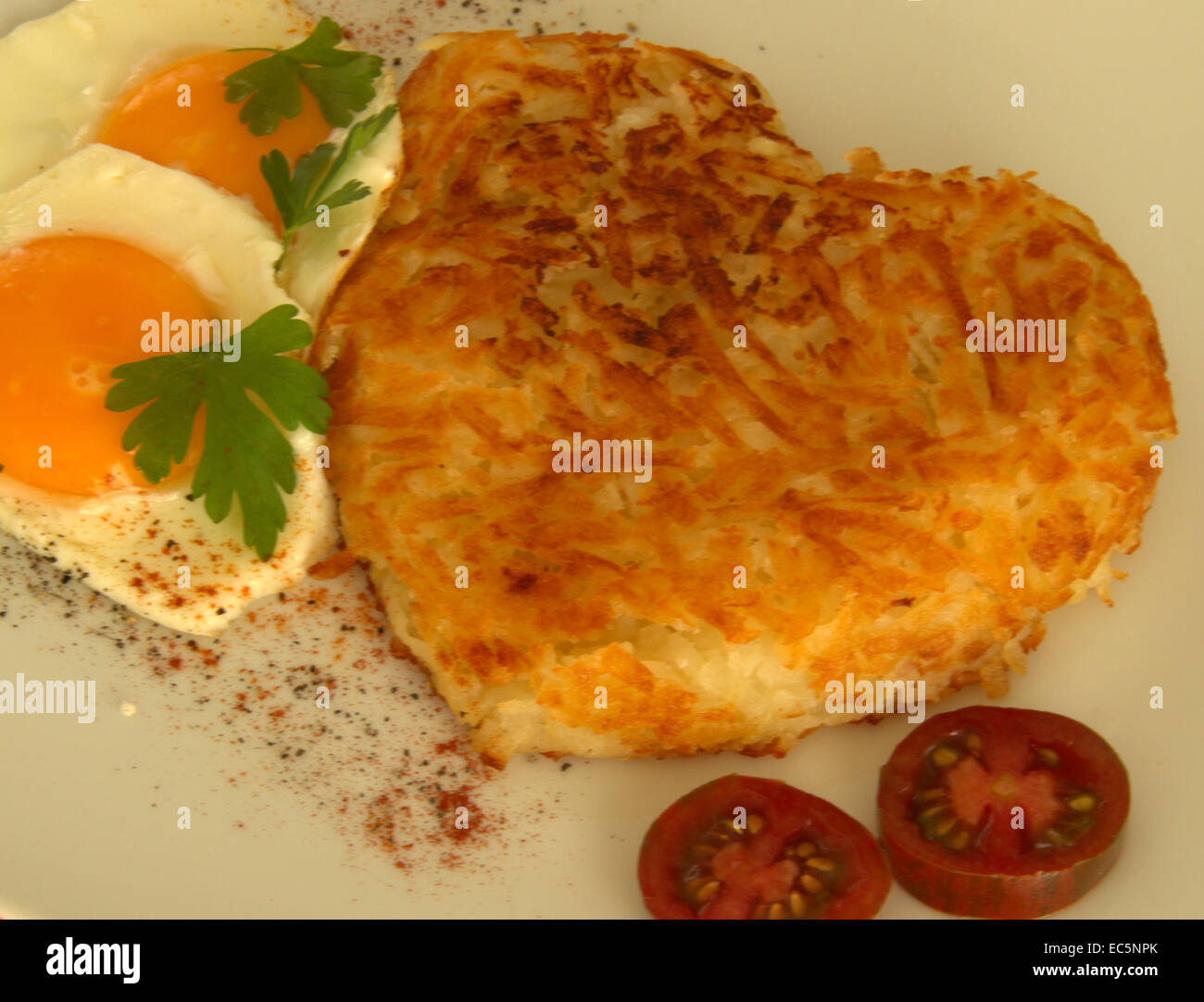 Swiss röstinchen con uova fritte e il pomodoro, la patata hash brown a forma di cuore Foto Stock