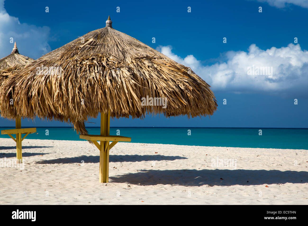 Gli ombrelli di erba lungo la spiaggia di sabbia bianca a Eagle Beach, Aruba, Antille Foto Stock