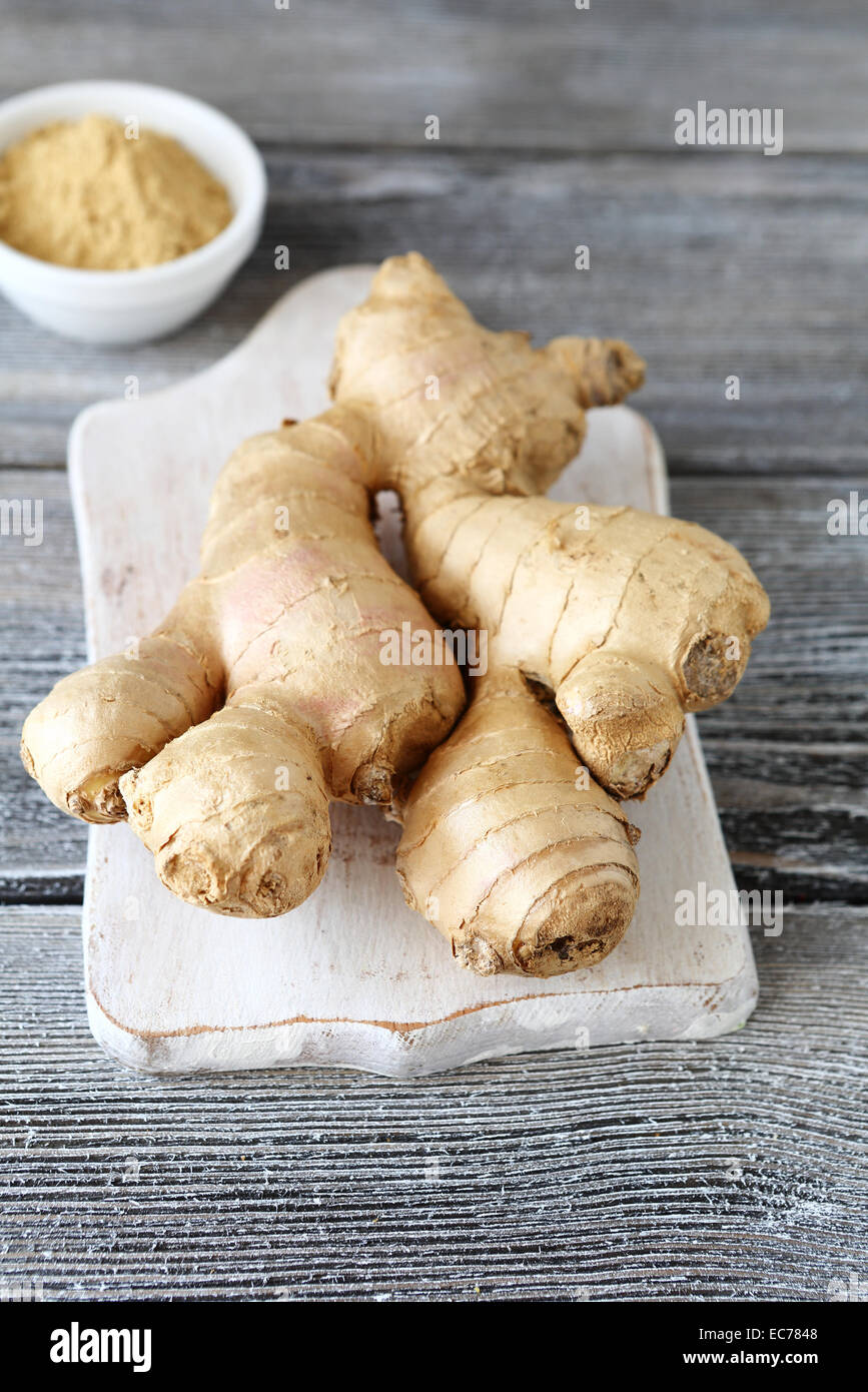 Lo zenzero piccante su un tagliere su sfondo di legno Foto Stock