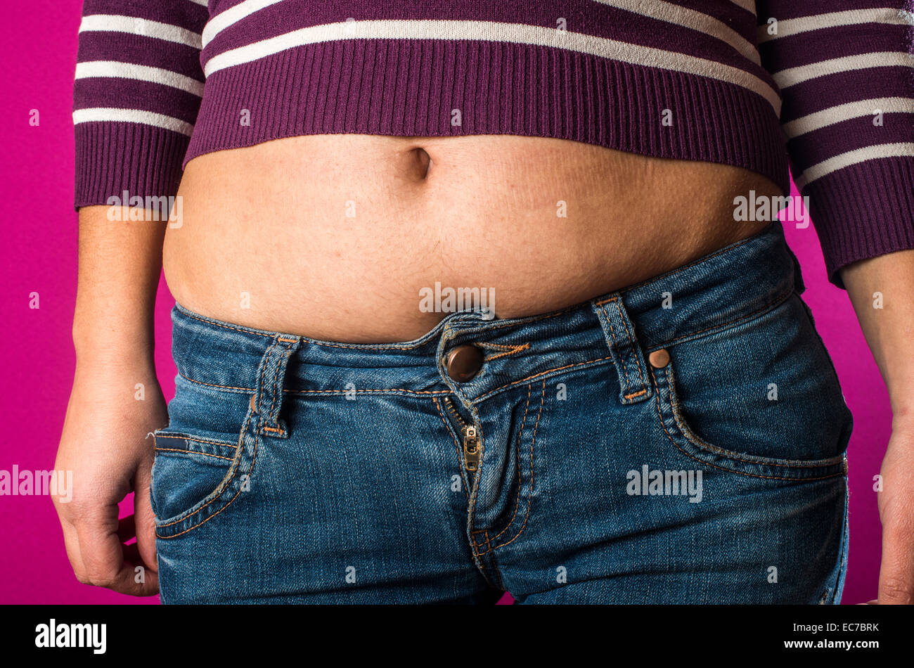 Donna con jeans mostra il suo ventre. Il sovrappeso. Foto Stock