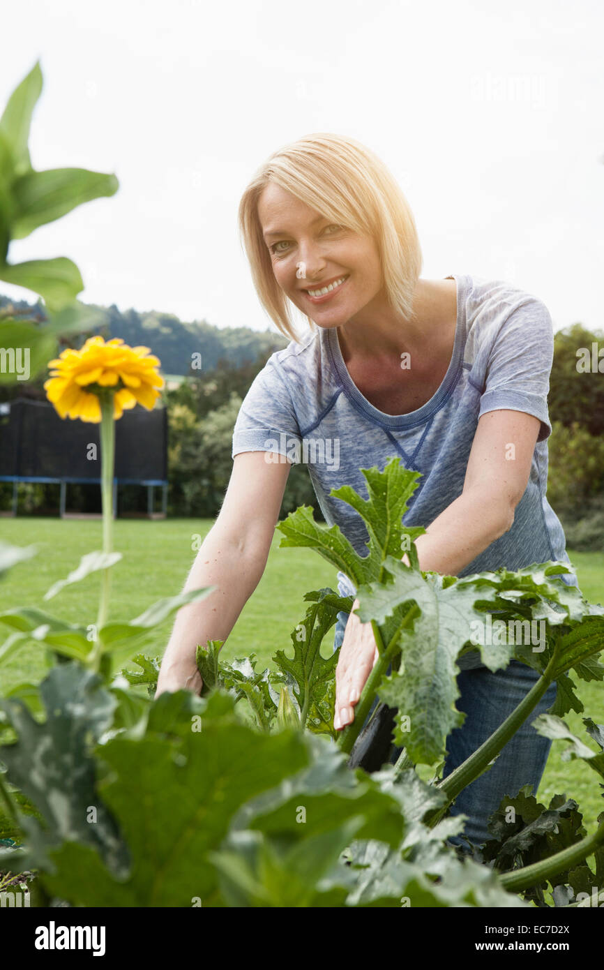 Donna sorridente lavora in giardino Foto Stock