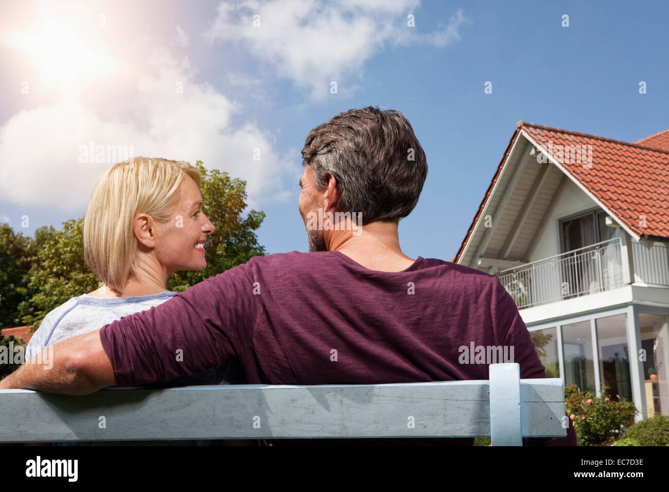 Vista posteriore della coppia matura seduta sul banco in giardino Foto Stock