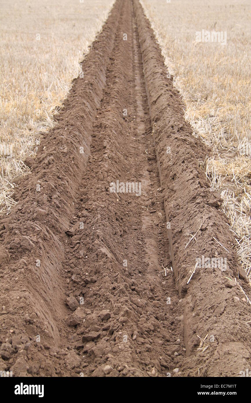 Un profondo solco arato su un campo di agricoltori. Foto Stock