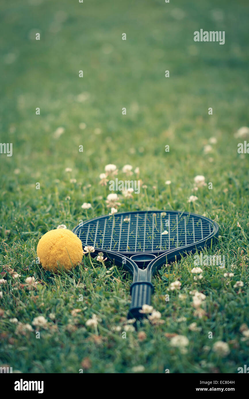 Plastica racchetta da tennis, palla gialla sull'erba Foto Stock