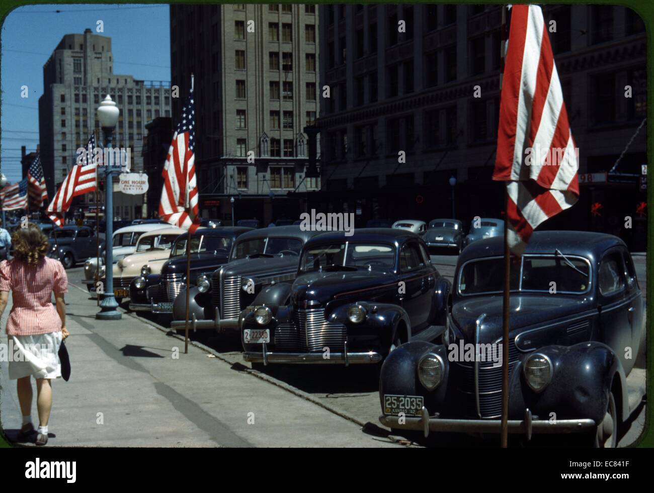 Strada di Lincoln, Nebraska, Stati Uniti d'America che mostra una linea di automobili parcheggiate davanti a parecchie bandierine americane Foto Stock
