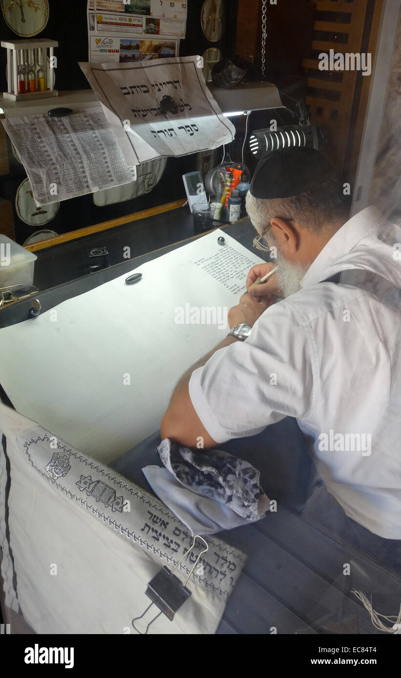 Torah Scribe in Israele scrive con cautela il vecchio testamento a mano su una speciale carta pergamena o scorr. Foto Stock
