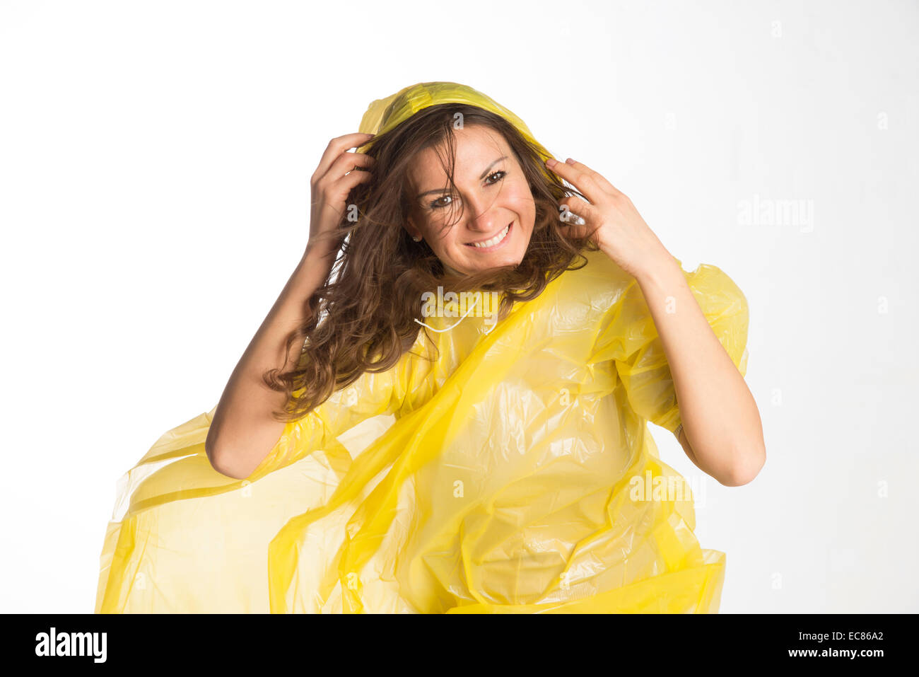 Donna che indossa un giallo poncho di plastica e trattenere il cofano in umidità condizioni ventose Foto Stock