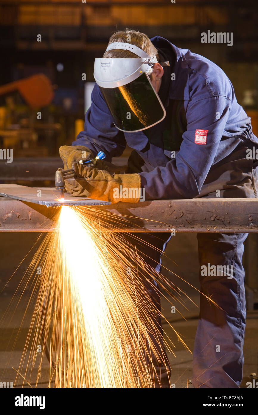Un artigiano di indossare dispositivi di protezione individuale durante il lavoro con acciaio e utensili a mano in un laboratorio industriale nel Regno Unito Foto Stock