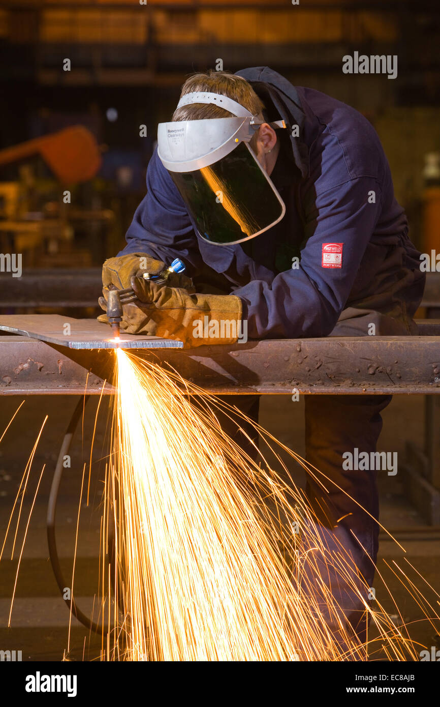 Un artigiano di indossare dispositivi di protezione individuale durante il lavoro con acciaio e utensili a mano in un laboratorio industriale nel Regno Unito Foto Stock