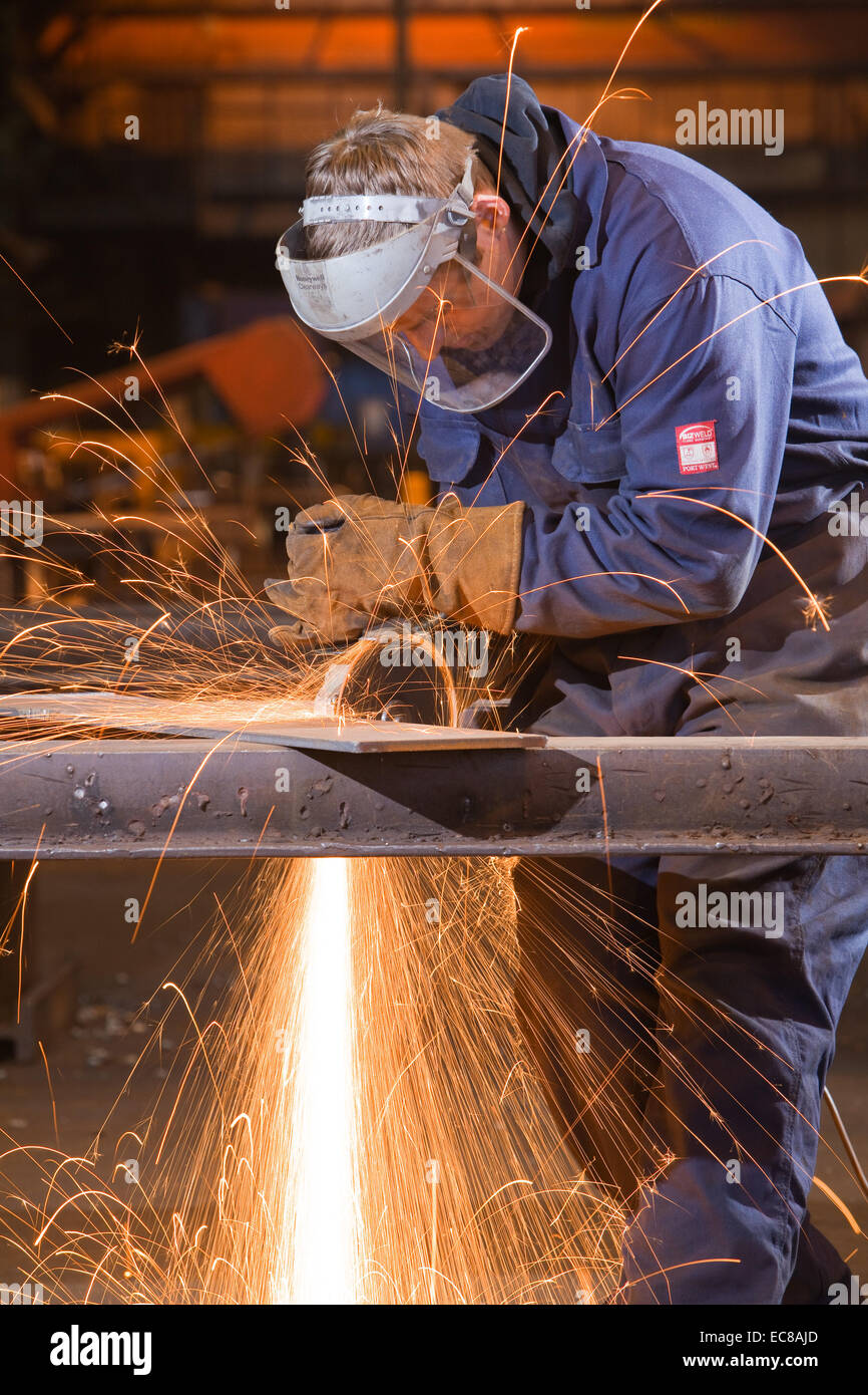 Un artigiano di indossare dispositivi di protezione individuale durante il lavoro con acciaio e utensili a mano in un laboratorio industriale nel Regno Unito Foto Stock