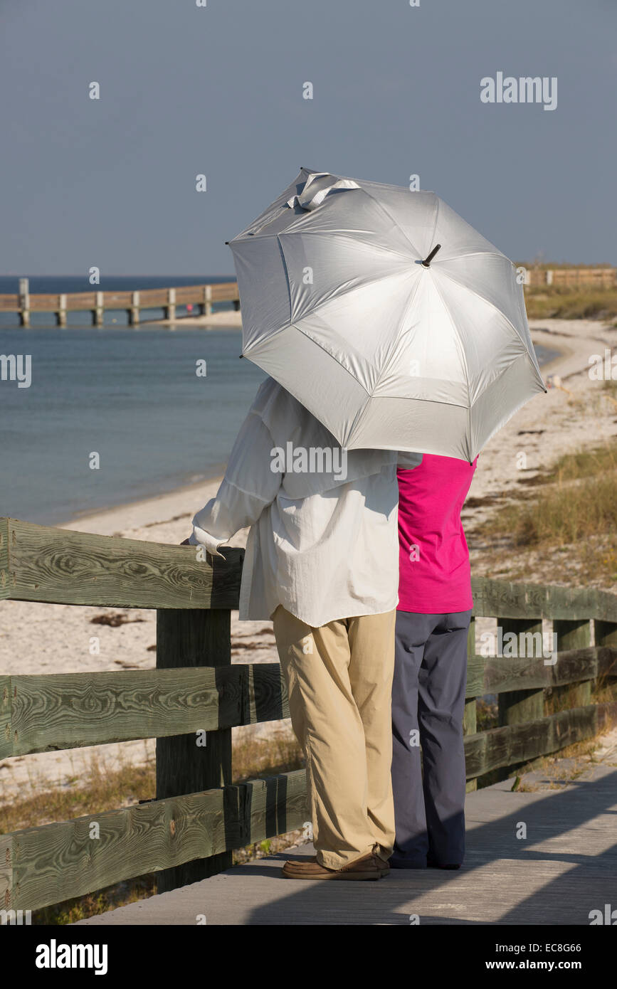 Vacanziere azienda protezione UV ombrello lungo le coste della Florida USA Foto Stock