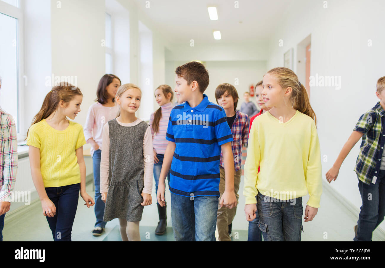 Gruppo di sorridere i bambini a scuola a piedi in corridoio Foto Stock