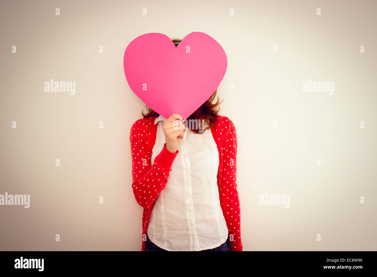 Tanga giovane ragazza con un ritaglio di carta cuore davanti al suo volto Foto Stock