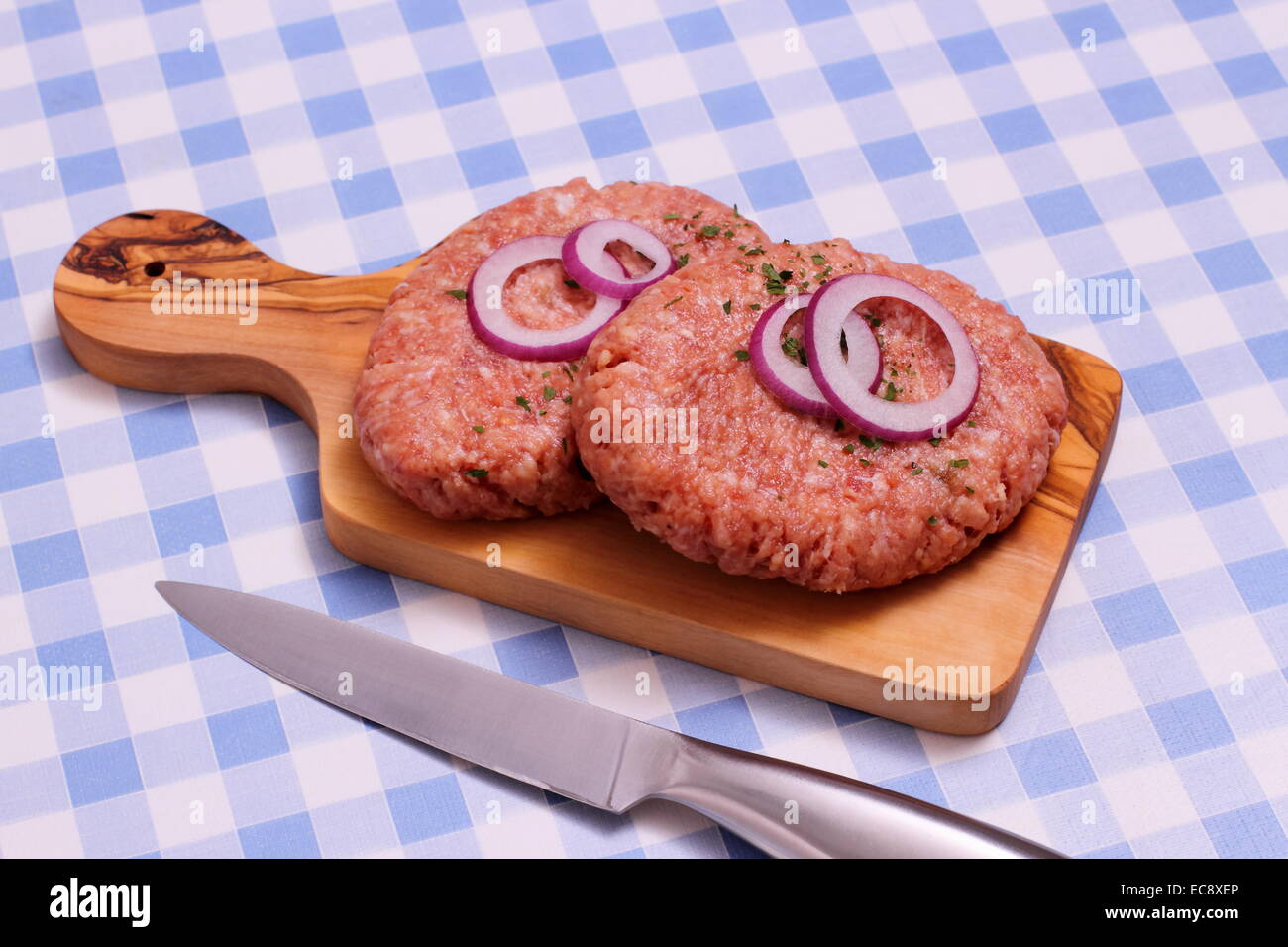 Due hamburger sul tagliere di legno, bianco e blu a quadretti Foto Stock