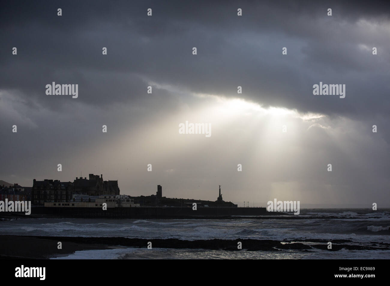 Aberystwyth, Wales, Regno Unito. Il 10 dicembre 2014. Dopo una giornata di forte vento e mare mosso, drammatica raggi di sole versare fuori da tra Dark nuvole temporalesche. Credito: Alan Hale/Alamy Live News Foto Stock