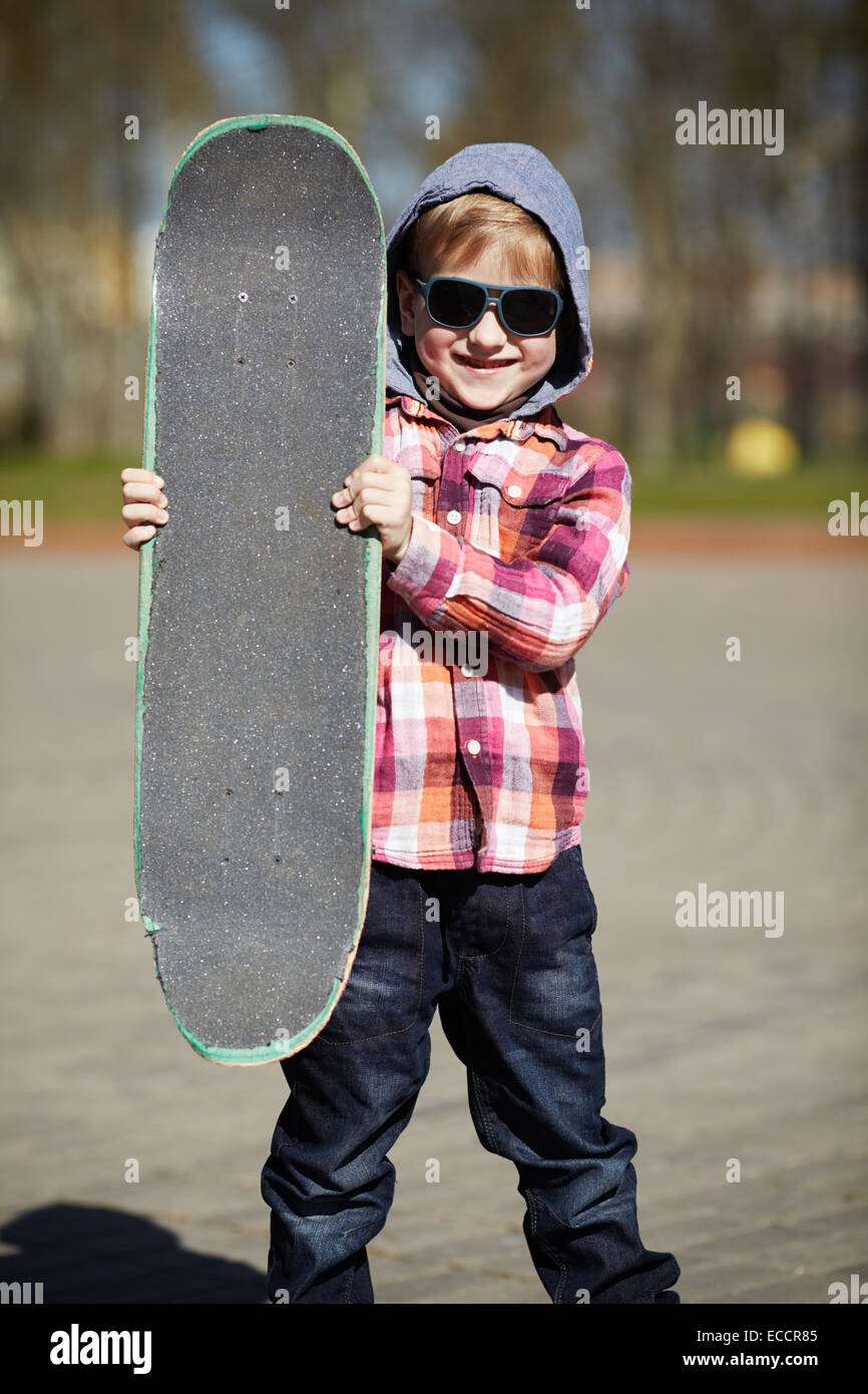 Ragazzino con lo skateboard su strada Foto Stock