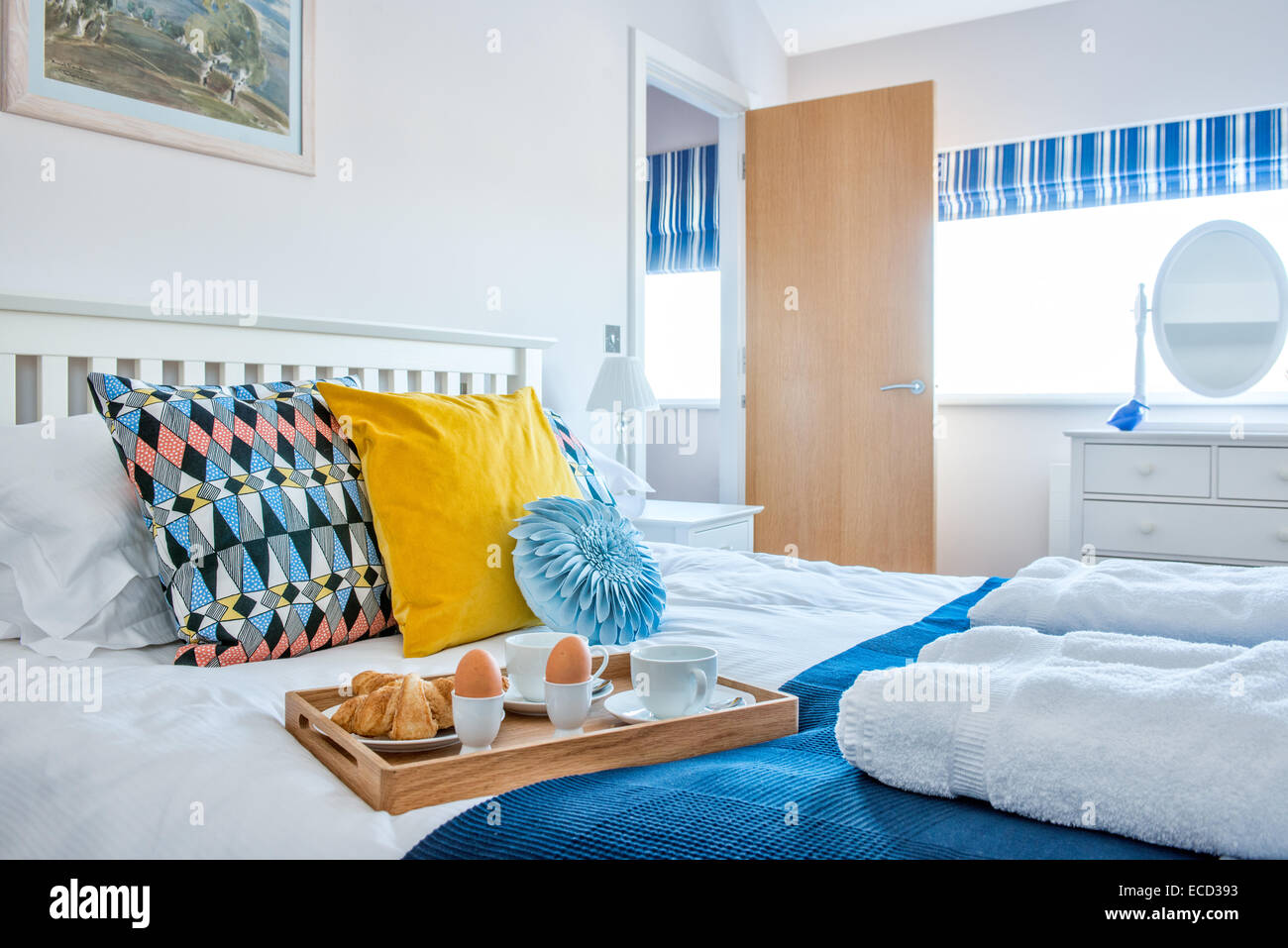 Uova sode, cornetti e tè per la colazione a letto su un vassoio in un colorato, fresche, arioso, soleggiato contemporanee camere da letto Foto Stock