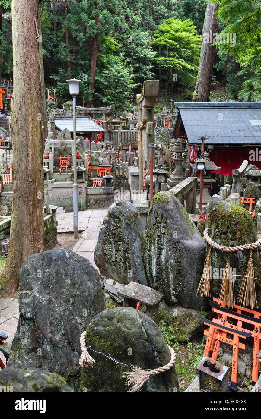 Cimitero shintoista presso il santuario di Fushimi Inari-taisha, Kyoto, Giappone, con magiche kitsune (volpi) e offerte di porte torii rosse in miniatura Foto Stock