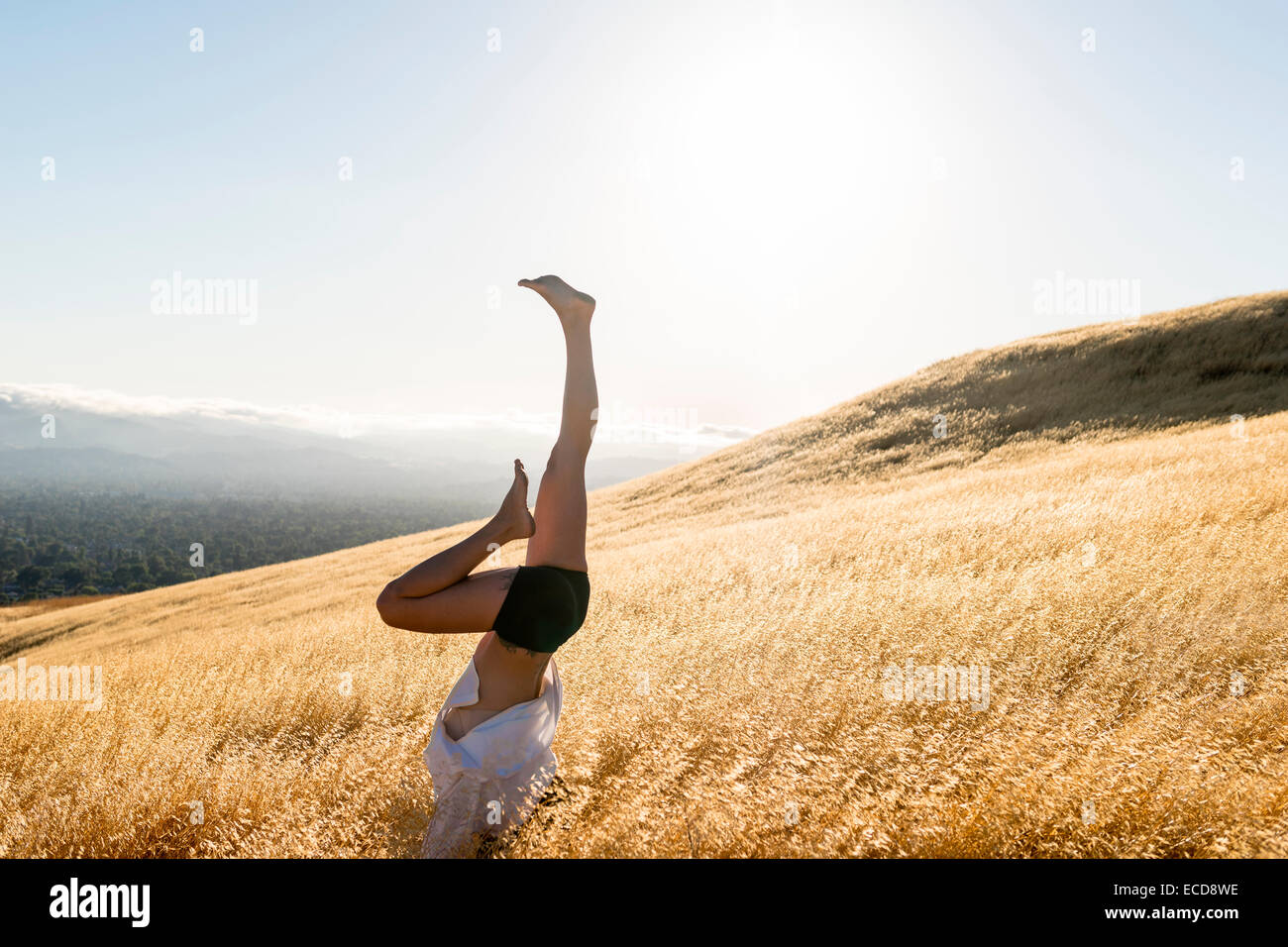 Donna di eseguire handstand sulle assolate colline Foto Stock