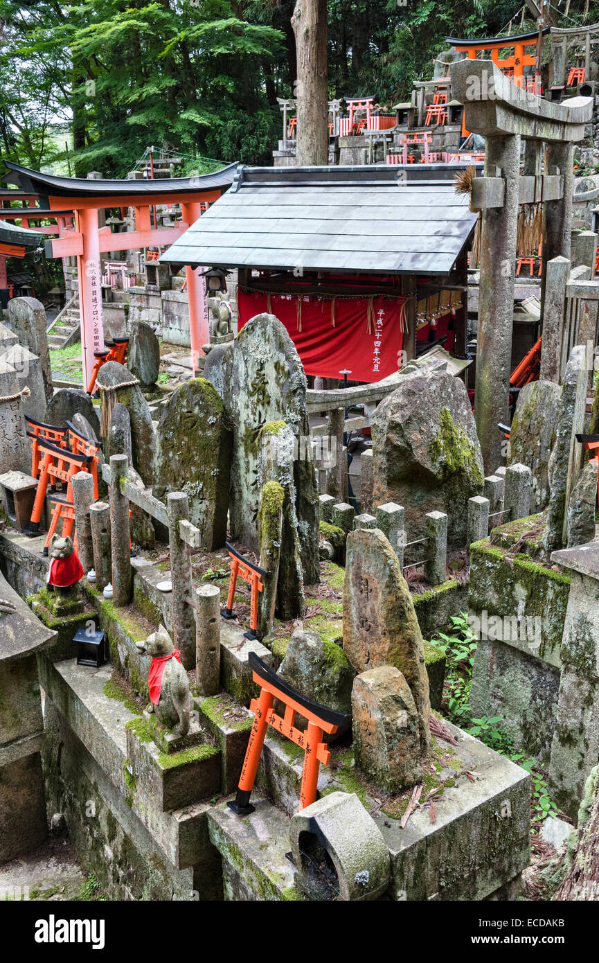 Kyoto, Giappone. Lo Shintoismo cimitero presso il Santuario di Fushimi-inari Taisha con kitsune (Volpi) e le offerte di miniatura torii gates Foto Stock