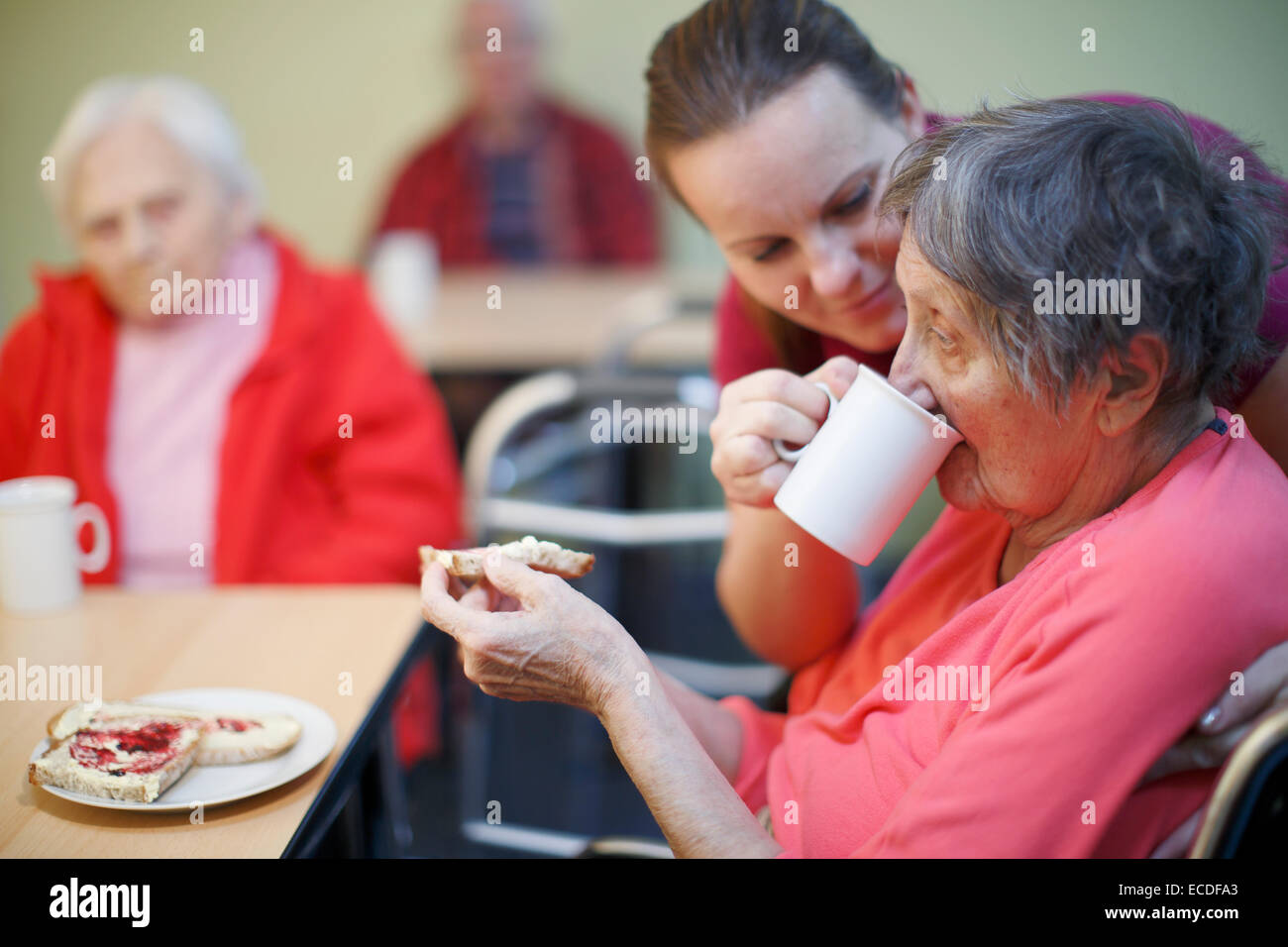 Donna, 81 anni, in una casa di cura, a colazione, supportato da un infermiere geriatrico, Foto Stock