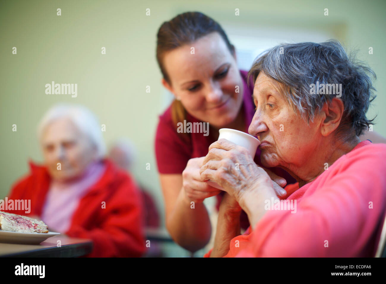 Donna, 81 anni, in una casa di cura, a colazione, supportato da un infermiere geriatrico, Foto Stock