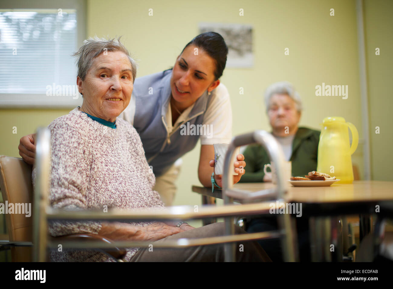Donna, 79 anni, in una casa di cura, a colazione, supportato da un infermiere geriatrico, Foto Stock