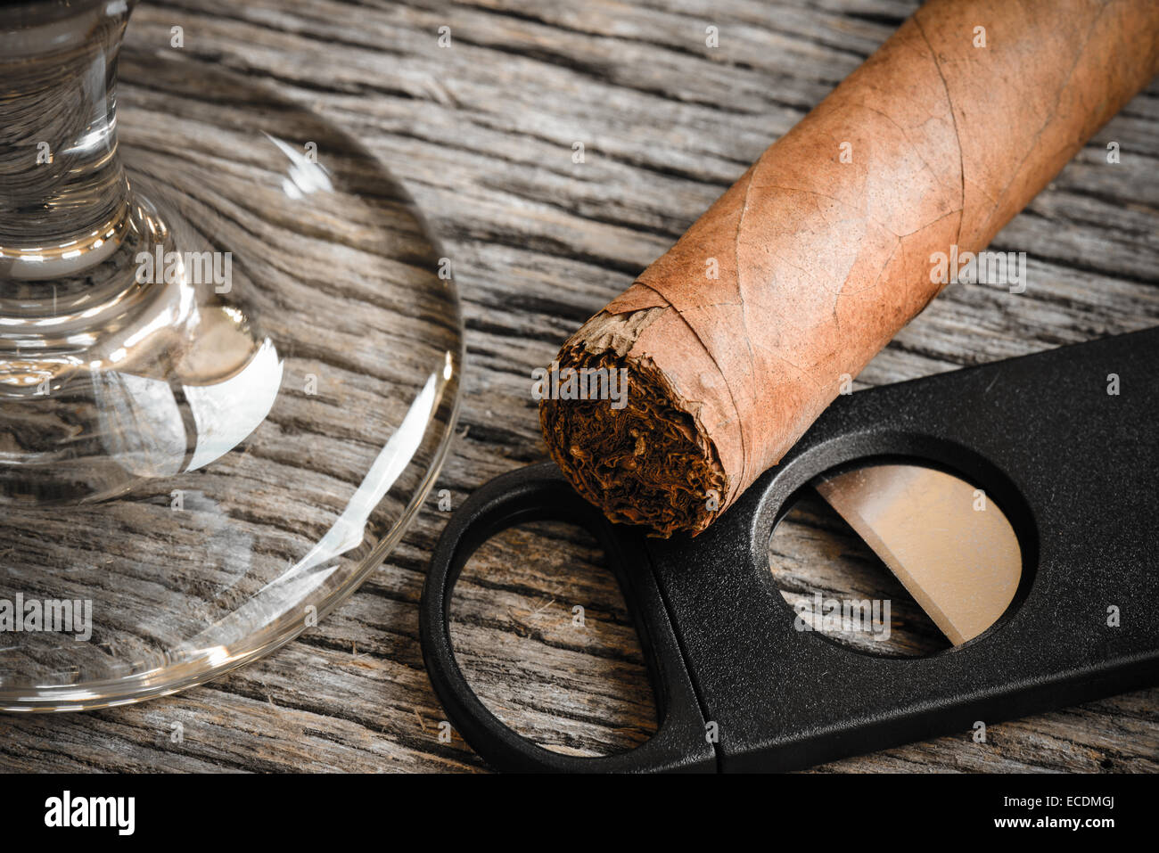 Il sigaro e la taglierina con bicchiere di brandy o Whiskey su sfondo di legno Foto Stock