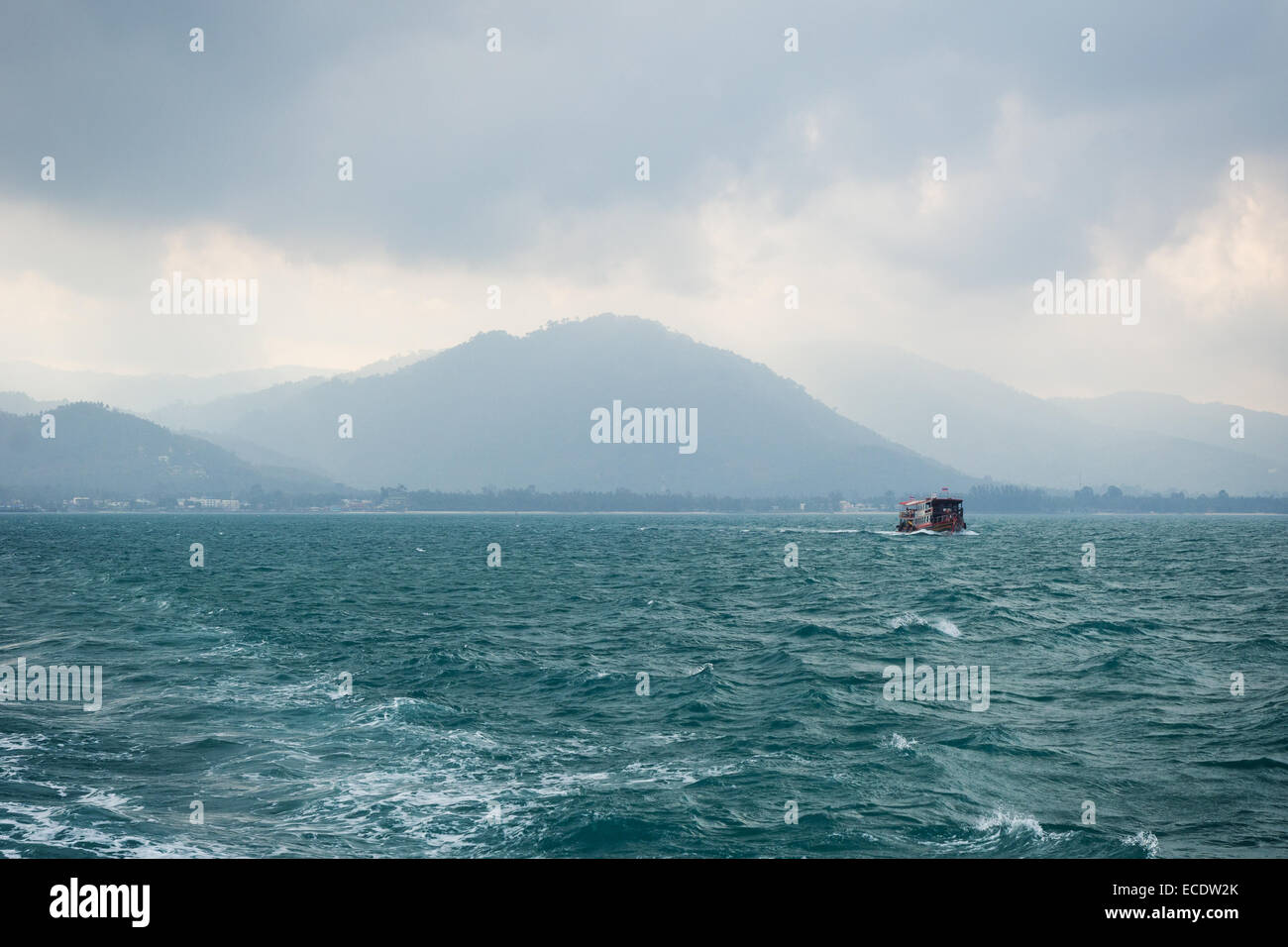 Una nave in mare ondoso al mattino nuvoloso, silhouette di montuoso Koh Samui, Thailandia Foto Stock