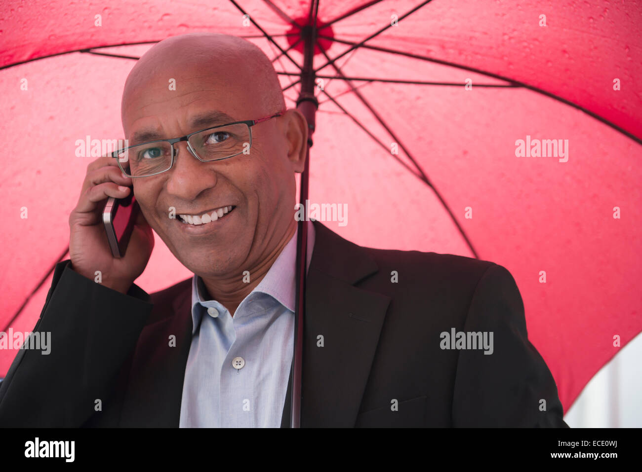 L'uomo africano ombrello di contenimento mobile phone positivo Foto Stock