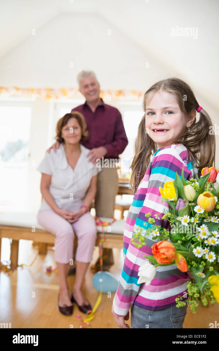 La nipote bouquet di handover alla nonna e nonno in background Foto Stock