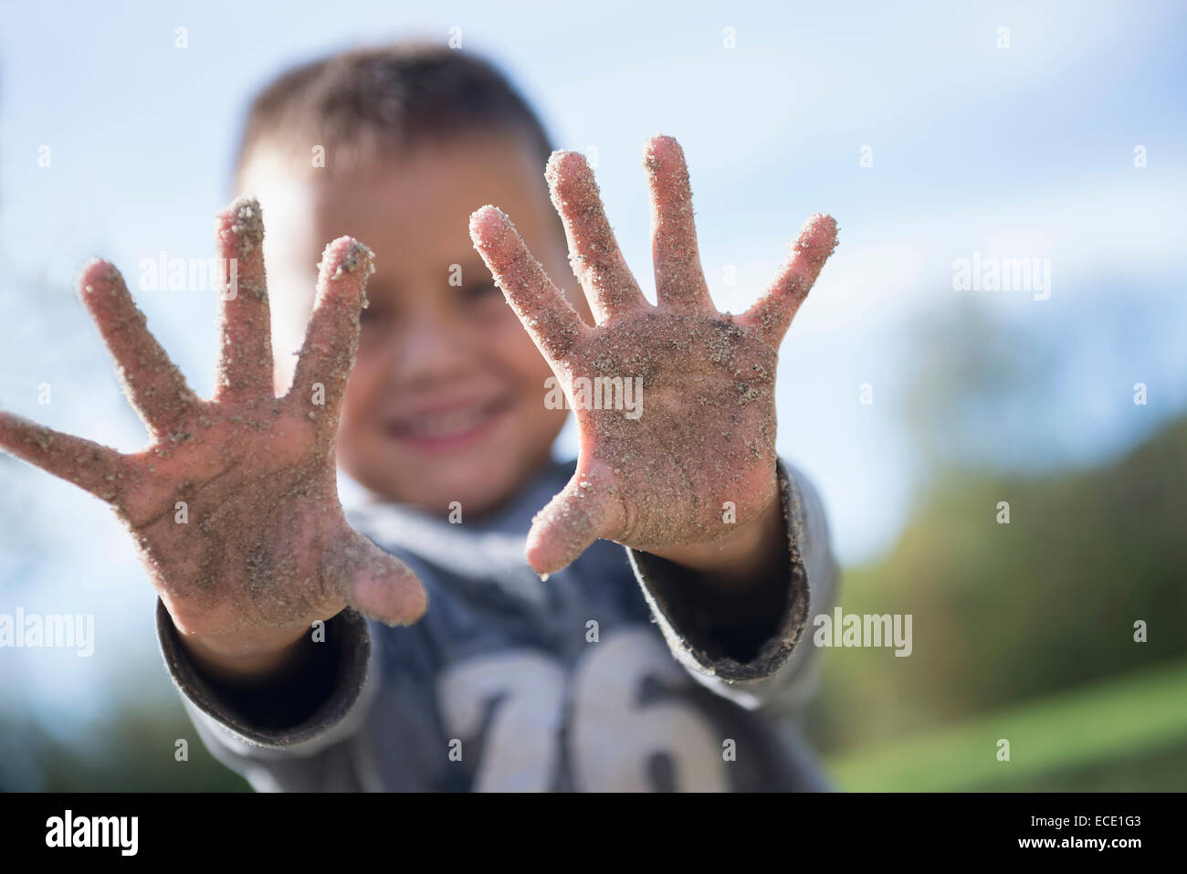 Piccolo Ragazzo che mostra le mani coperte parco giochi in sabbia Foto Stock