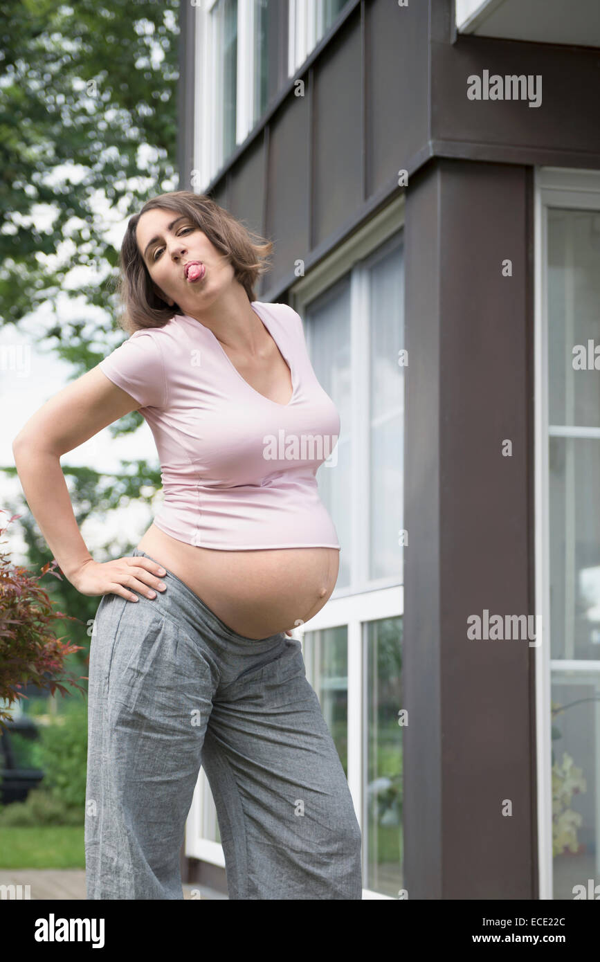 Con la lingua fuori cool donna incinta in posa Foto Stock