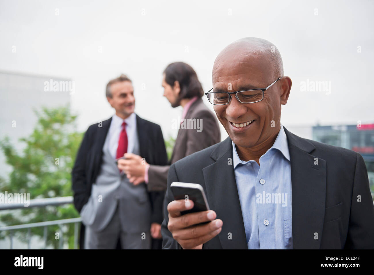 Tre uomini di affari africani SMS Smartphone agente immobiliare Foto Stock