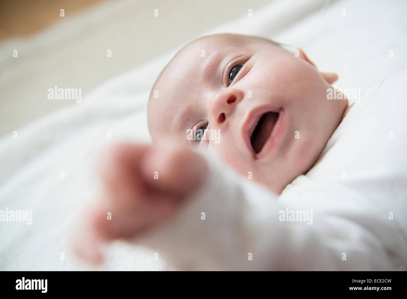 Baby boy sdraiato sul letto con la bocca aperta Foto Stock