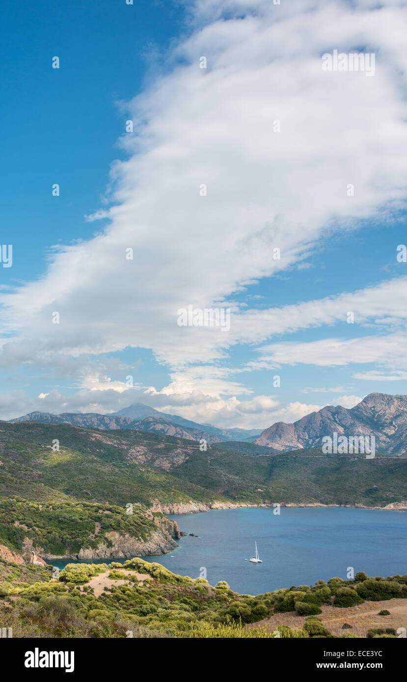 Baia con una barca a vela, costiere e del paesaggio di montagna, il Golfo di Porto, Corsica, Francia Foto Stock