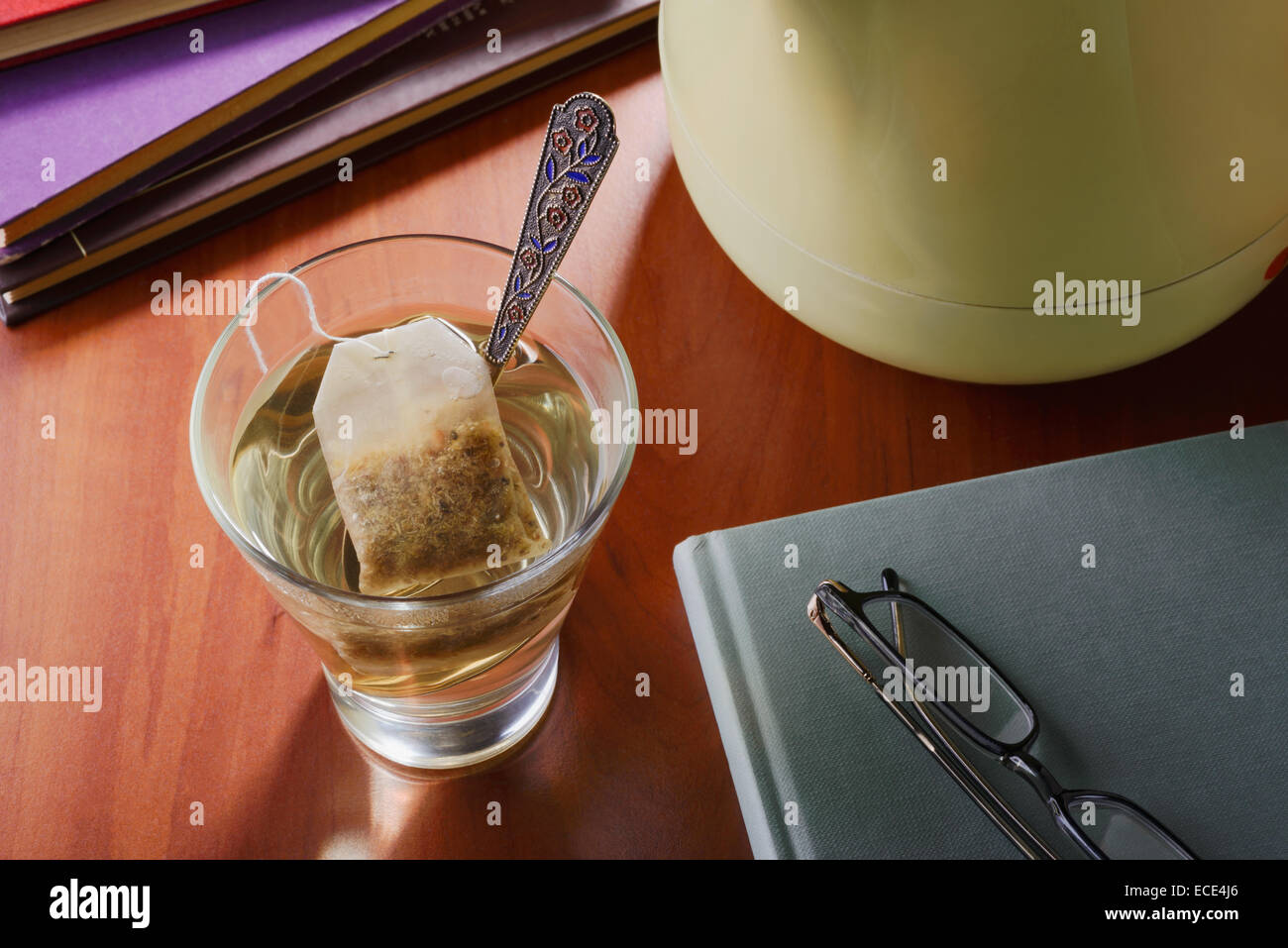 Un momento di relax sorseggiando un bicchiere di tè caldo o altri tisane, durante la lettura di libri Foto Stock