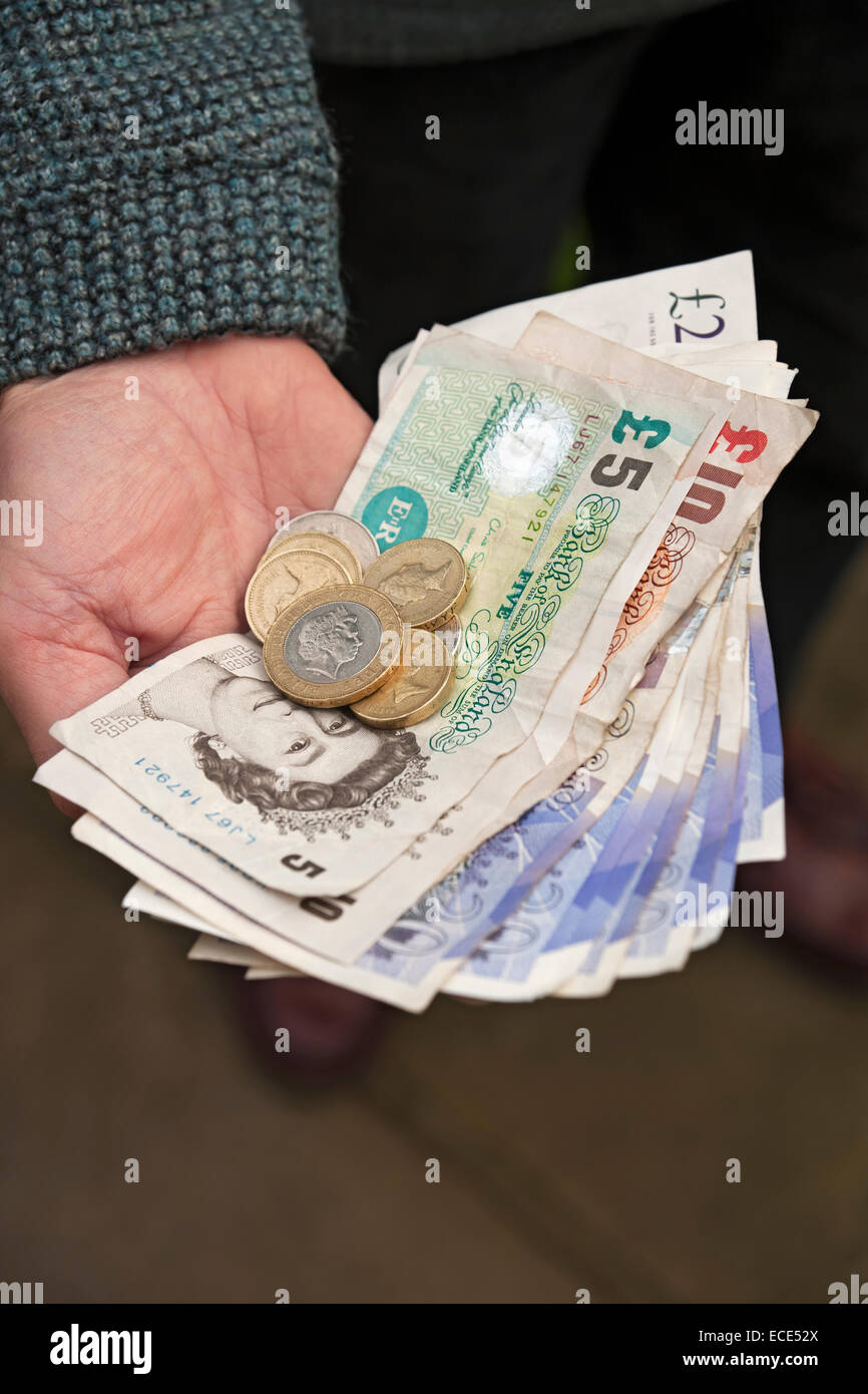 Primo piano di una persona che detiene banconote paganti banconote banconote in moneta inglese banconote in contanti monete Inghilterra Regno Unito Regno Unito Gran Bretagna Foto Stock