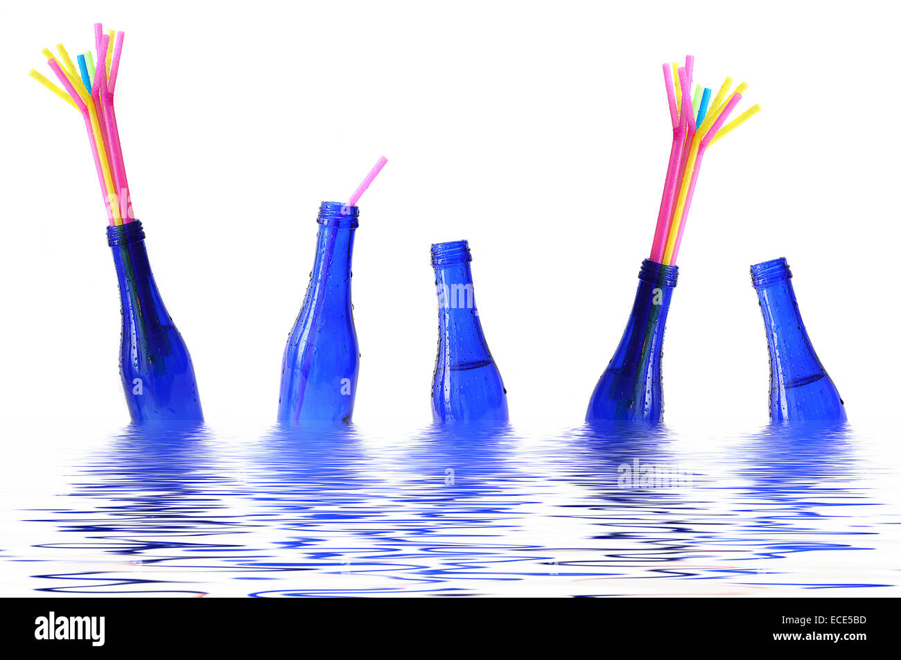 Bottiglie di colore blu con cannucce colorate galleggianti in acqua Foto Stock