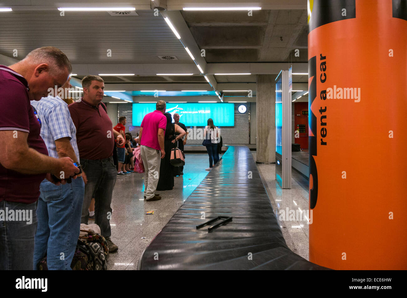 Passeggeri in attesa di bagagli in un carosello aeroportuale Foto Stock