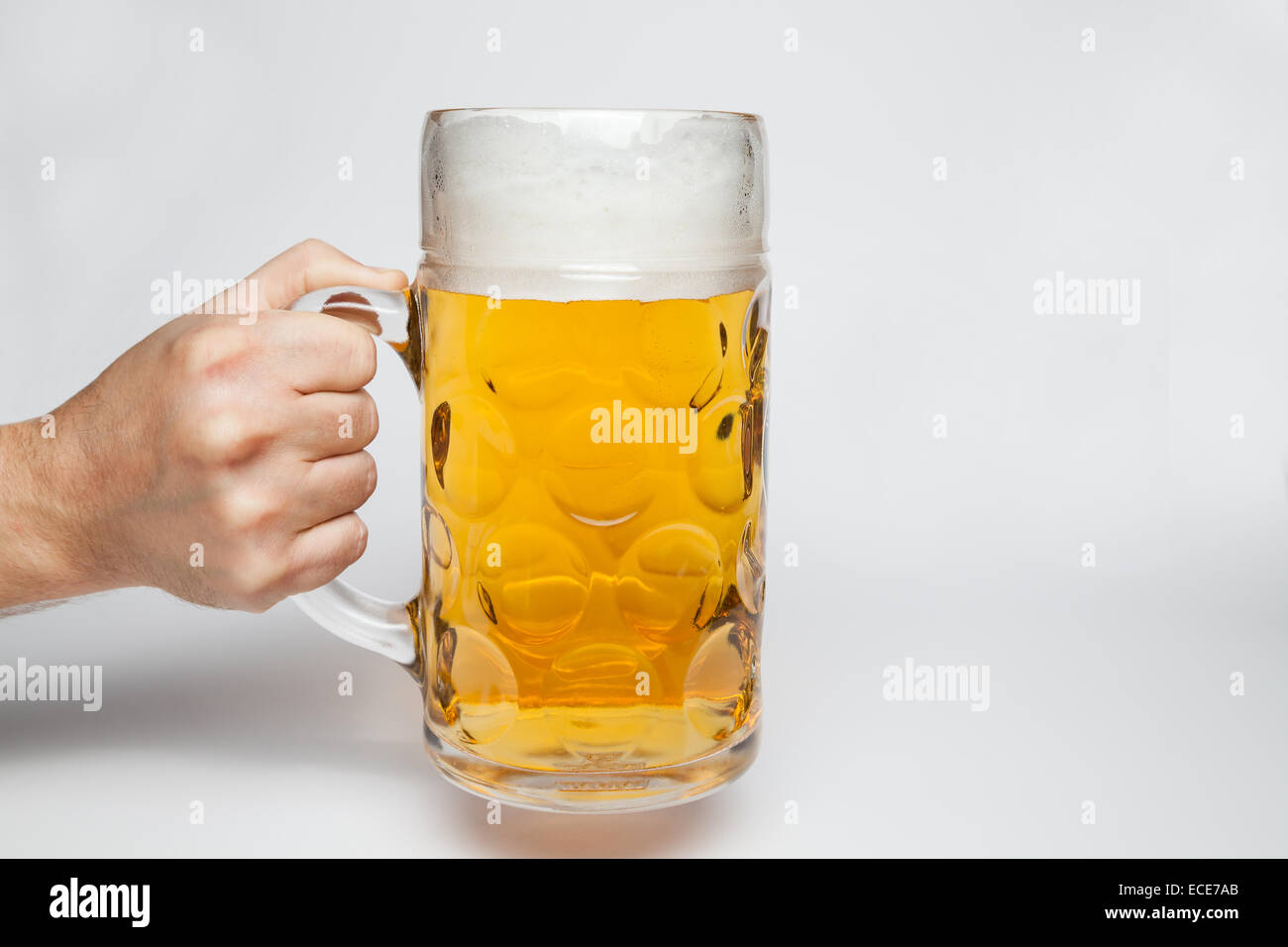 Mano che tiene un boccale di birra su sfondo grigio Foto Stock