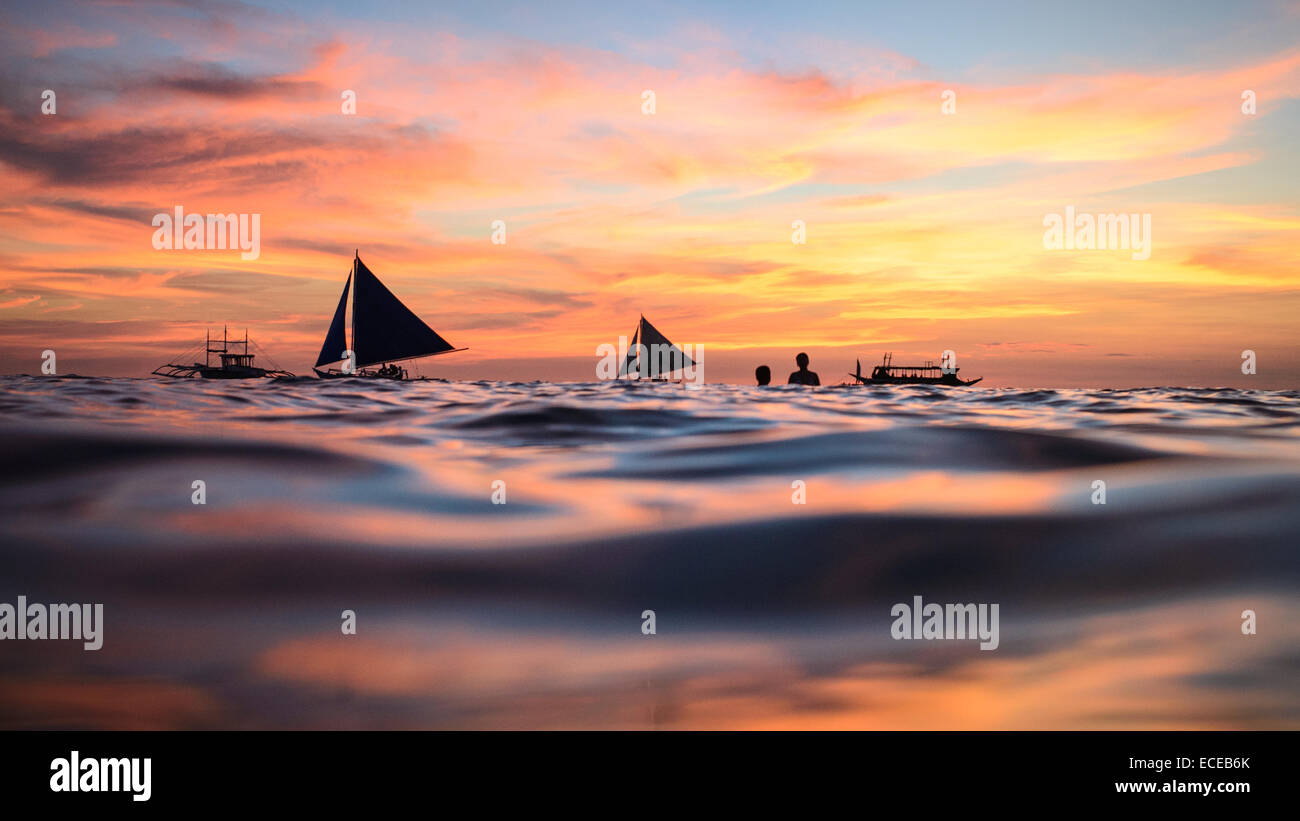 Silhouette di barche e persone che nuotano al tramonto, Boracay, Aklan, Western Visayas, Phillipines Foto Stock