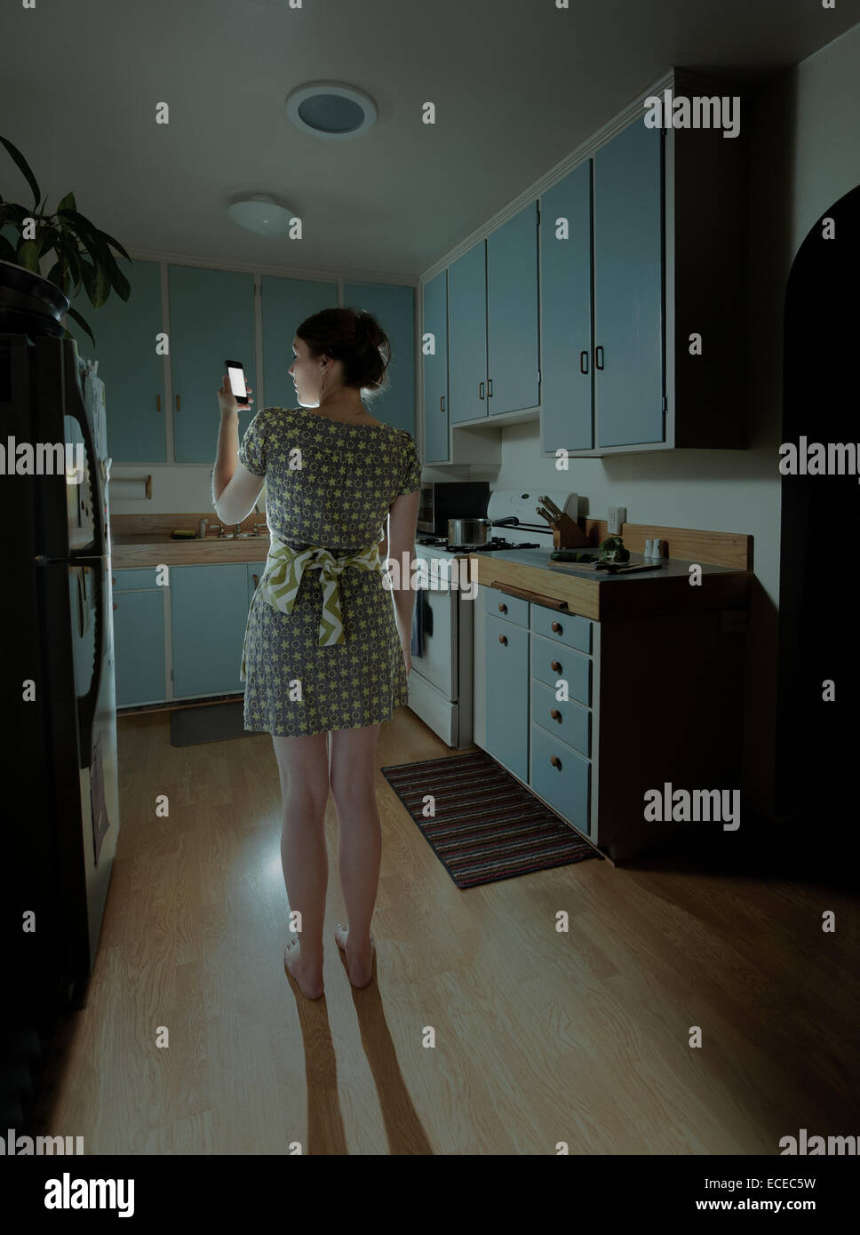 Donna con lo smartphone in cucina di notte Foto Stock