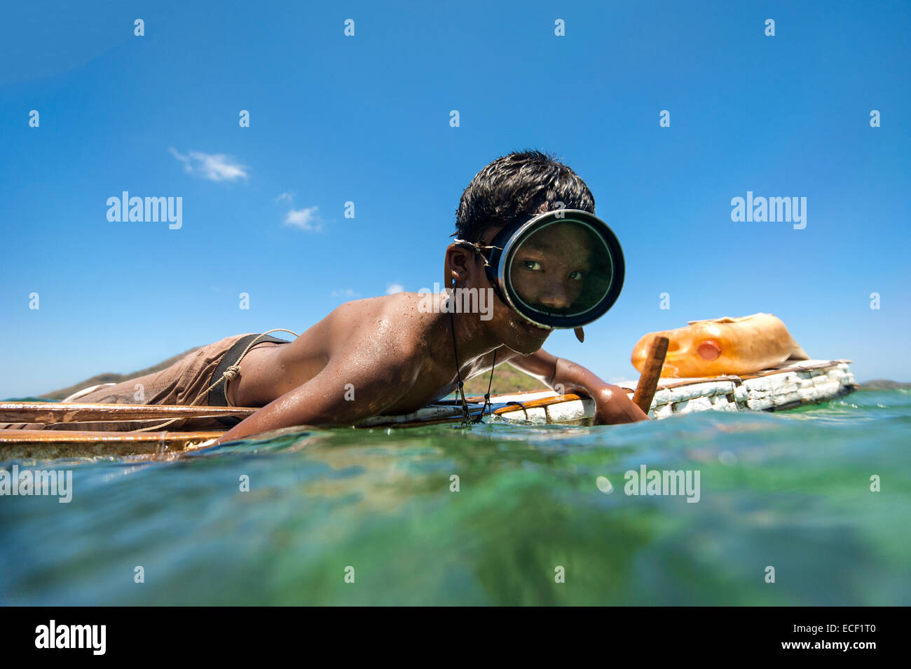 Tagbanua ragazzo su una floating bulsa cercando il polpo con il suo fucile Foto Stock