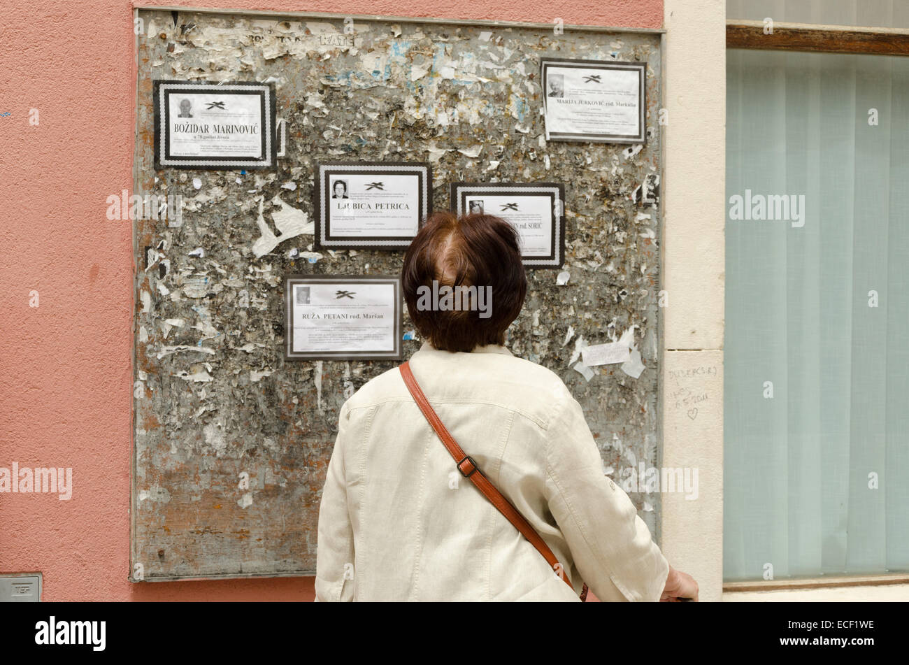 ZADAR, Croazia - 21 Maggio 2013: vecchia donna in piedi la lettura della morte avvisi che in Croazia sono pubblicati su annuncio pubblico Foto Stock