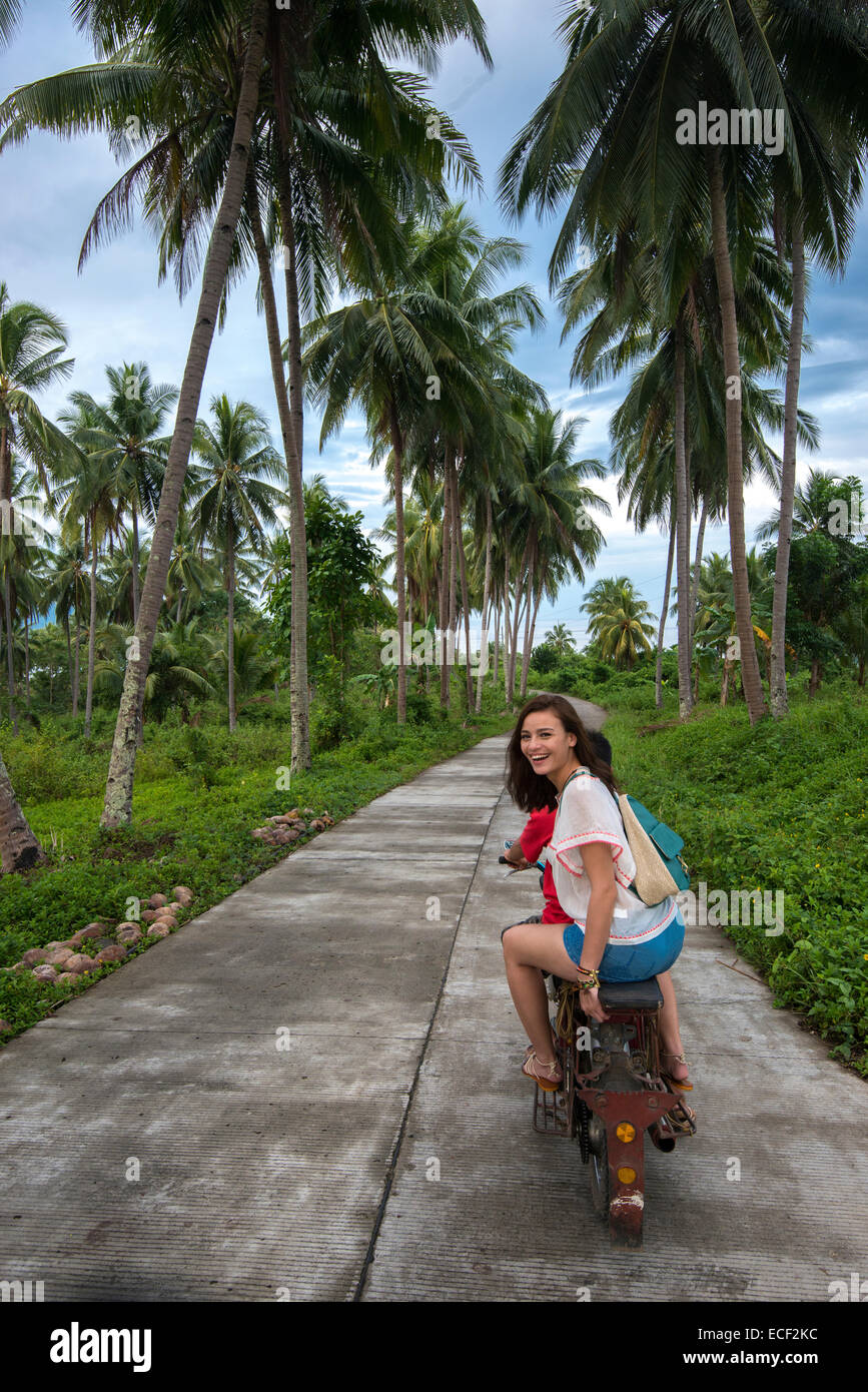La donna in sella a una motocicletta taxi su una strada rurale nelle Filippine Foto Stock